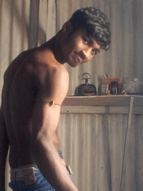 a man without a shirt is standing in front of a wall