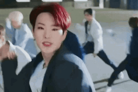 a young man with red hair is standing in front of a group of young men .