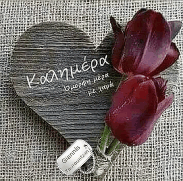 two red roses are sitting on a wooden heart with a tag on it .