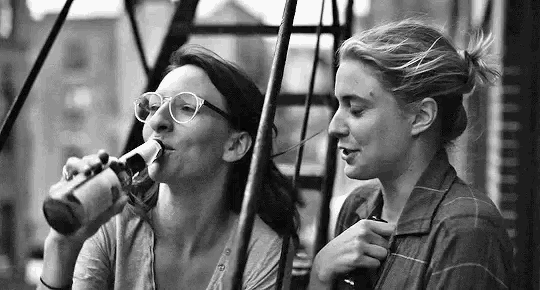 a black and white photo of two women drinking beer .