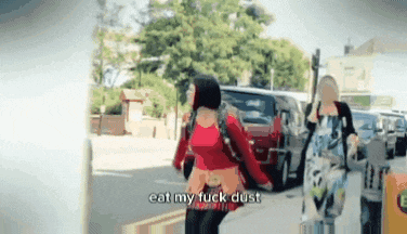 a woman walking down a street with the words eat my fuck dust on the bottom