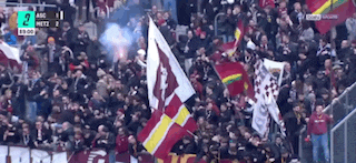 a crowd of people in a stadium watching a soccer game with a score of 2 to 1