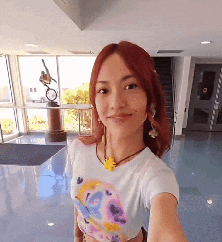 a woman with red hair is taking a selfie in front of a window