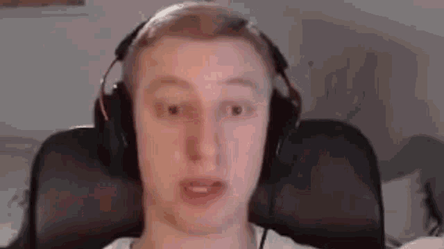 a man wearing headphones is sitting in a chair and making a face .