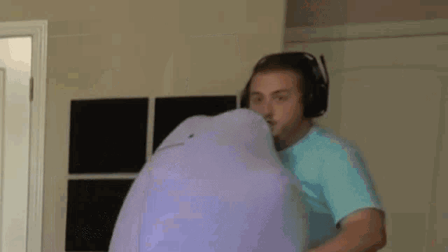a man wearing headphones is holding a purple stuffed animal in his hands .