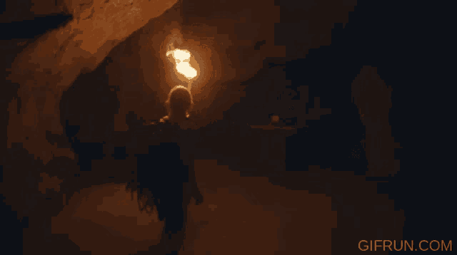 a person is holding a torch in a cave and the website gifrun.com is visible in the corner