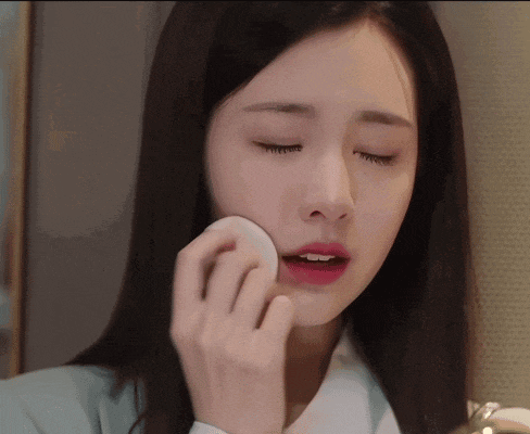 a woman is applying makeup to her face with a cotton pad