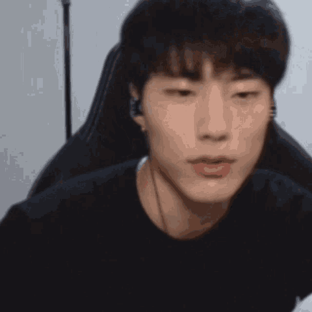 a young man is sitting in a chair wearing headphones and looking at the camera .