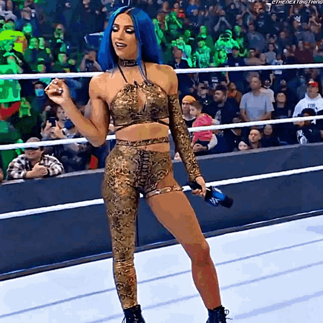 a woman with blue hair is standing in a ring holding a microphone .