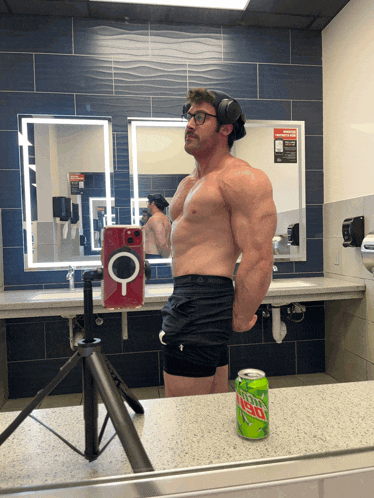 a man taking a picture of himself in a bathroom with a can of mountain dew on the counter