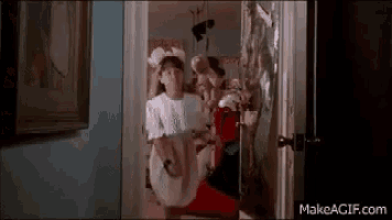 a girl in a white shirt is standing in a doorway holding a blanket .