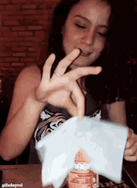a woman is holding a piece of paper with the gifsdayrol logo in the corner