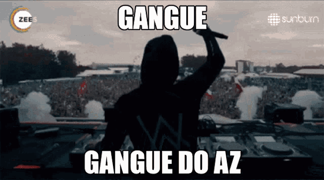 a man in a hood is holding a microphone in front of a crowd and says gangue