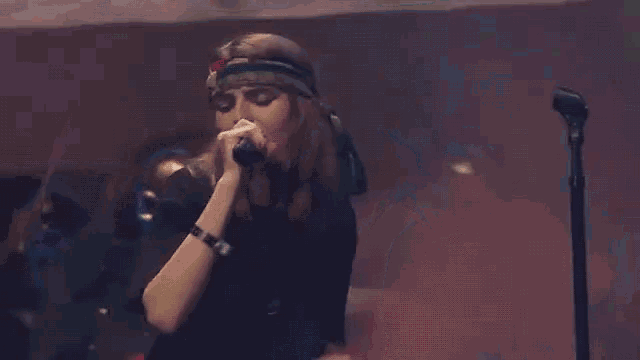 a woman is singing into a microphone on a stage .