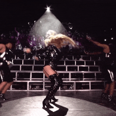 a woman wearing thigh high boots is dancing on stage