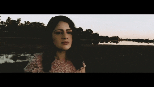 a woman in a lace dress is standing in front of a body of water