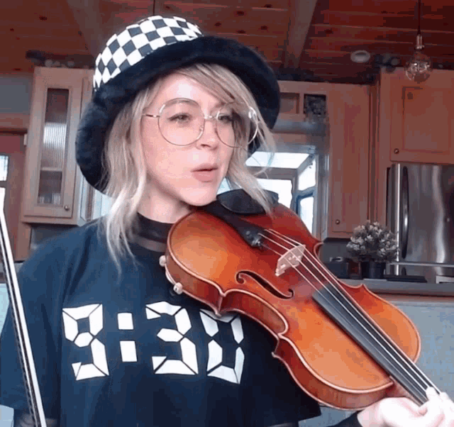 a woman is playing a violin and wearing a shirt that says 8:33