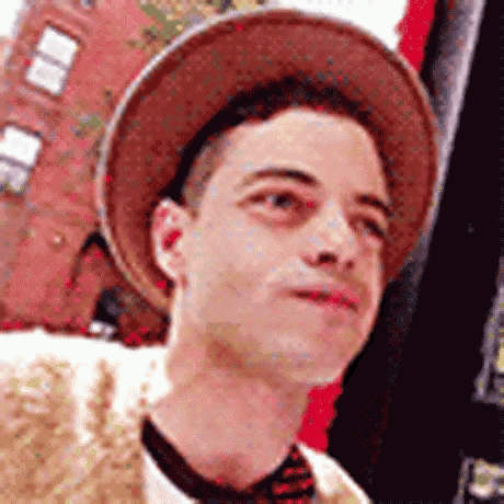 a man wearing a hat and a tie is looking up at something .