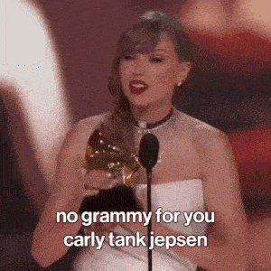 a woman in a white dress is holding a grammy and speaking into a microphone .