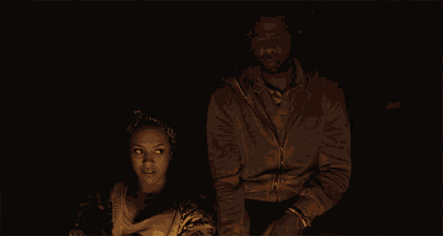 a man and a woman are sitting in front of a fire
