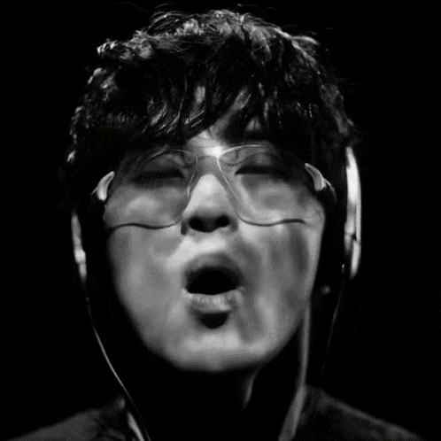 a black and white photo of a man wearing headphones covering his mouth with his hands