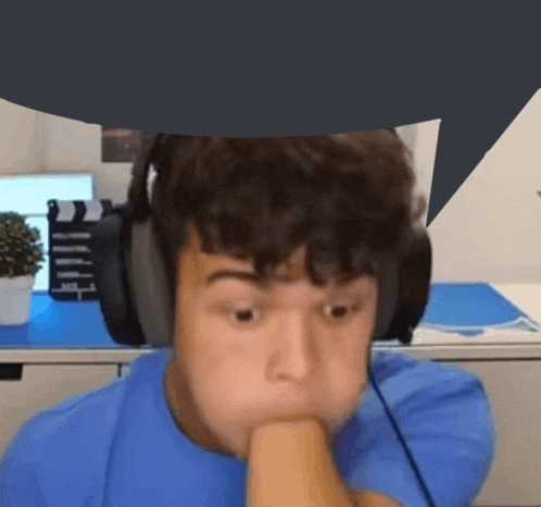 a young man wearing headphones looks at the camera