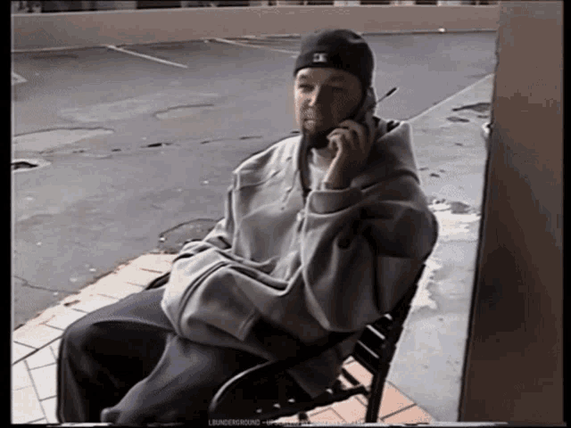a man sitting on a bench talking on a cell phone with the word underground on the bottom