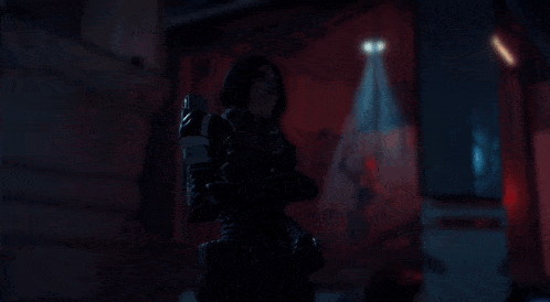 a woman in a futuristic suit is holding a rifle