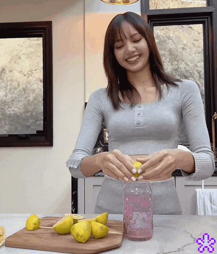 a woman is smiling while cutting lemons on a wooden cutting board