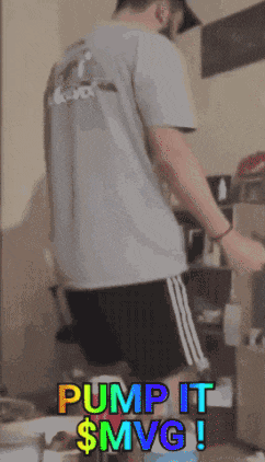 a man in a gray shirt and black shorts is standing in front of a computer and says pump it $mvg