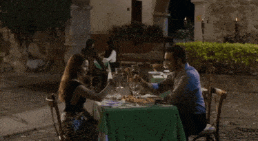 a woman is drinking a glass of wine while sitting next to a man