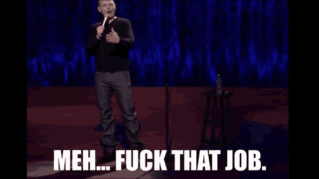a man is standing on a stage holding a microphone and saying meh fuck that job