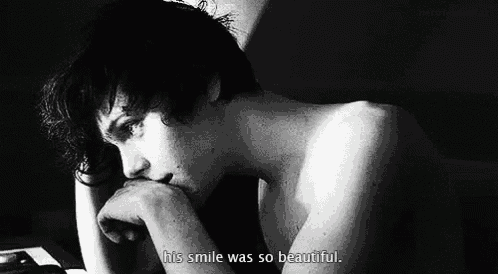 a black and white photo of a shirtless young man with his hand on his chin and the words `` his smile was so beautiful '' .