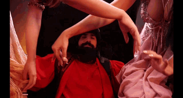a man with a beard is surrounded by three women