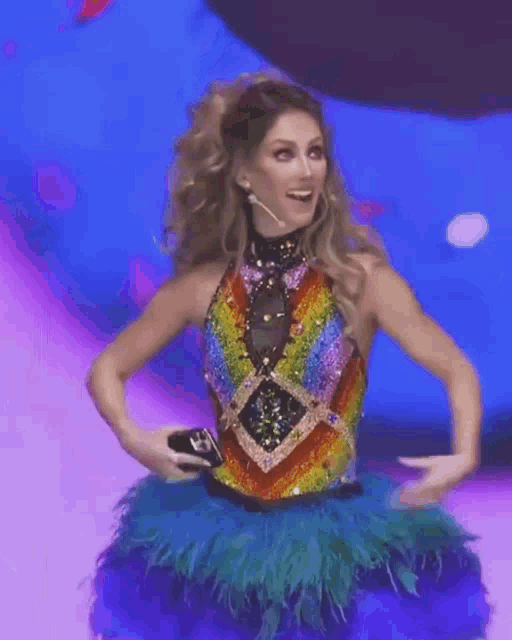 a woman in a colorful dress is standing on a stage with her hands on her hips