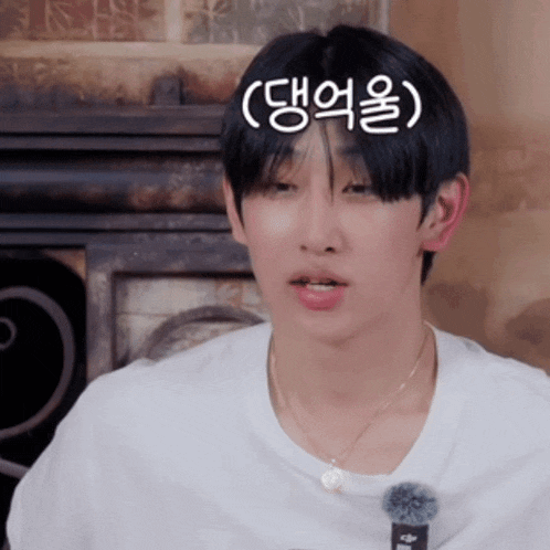 a young man wearing a white t-shirt and a necklace has korean writing on his forehead