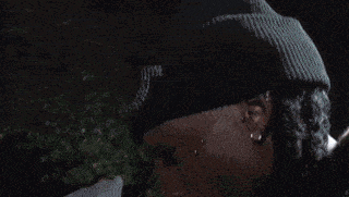 a person wearing a black hat is looking down at a dog .
