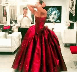 a woman in a red dress is standing in front of a mirror