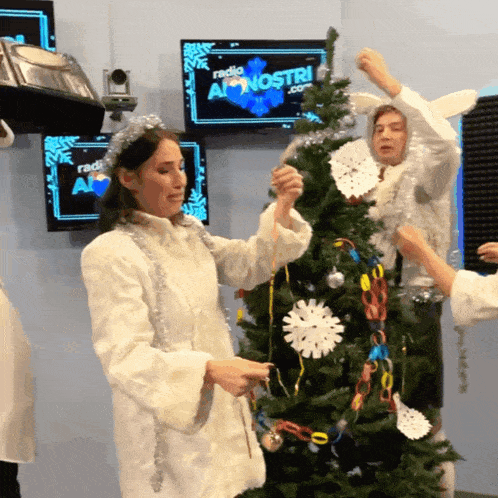a group of people decorating a christmas tree in front of a screen that says radio al nostri