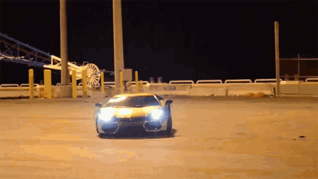 a yellow car is driving down a street at night