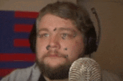 a man with a beard is wearing headphones and looking at a microphone