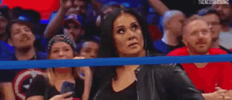 a woman is standing in a wrestling ring while another woman stands in the background .