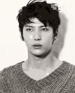 a young man wearing a sweater is looking at the camera in a black and white photo .