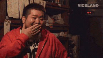 a man in a red jacket is covering his mouth with his hand ..