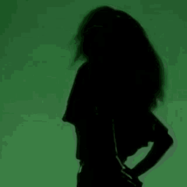 a woman is dancing in front of a green background .
