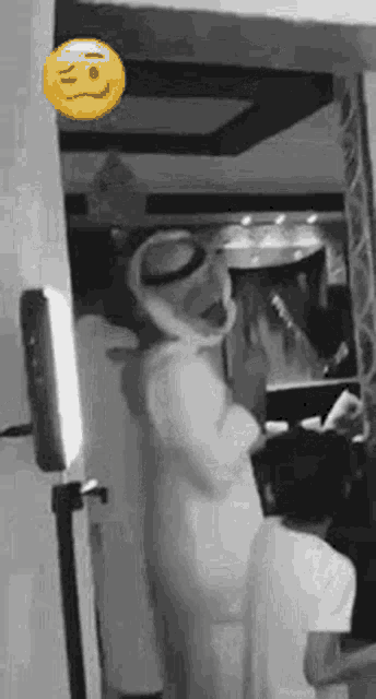 a man in a white robe is standing in a room with a smiley face on the wall .