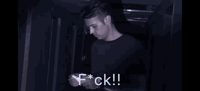 a man in a dark room with the word f * ck on the bottom