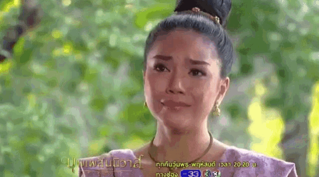 a woman with a bun on her head is crying in front of trees .