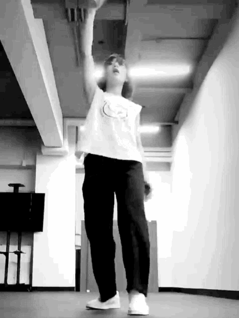 a black and white photo of a person dancing in a room with a ceiling .
