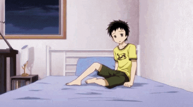 a boy is sitting on a bed wearing a yellow shirt with the letter r on it